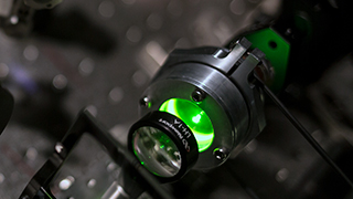 Close up image of an experiment with a green optical laser.